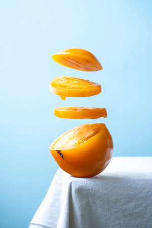 Yellow tomato slices levitating in the air isolated on blue background.の写真素材