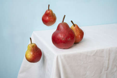 red pears on a blue background and white table.
