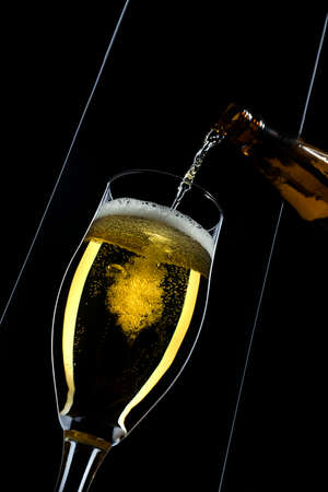 a beer pouring in a glass on a black backgroundの写真素材