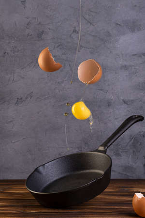 frying pan with levitation raw egg shell on wooden tableの写真素材