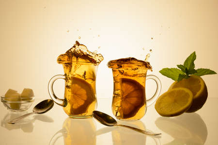 Cup of tea and glass teapot on glass with orange background