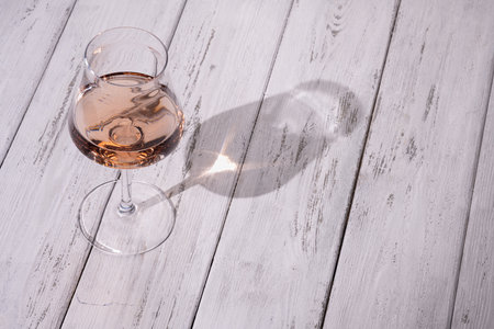 wineglass of pink wine on white wooden table. Rose wine in wineglass.
