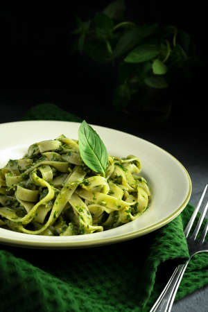 Pasta spaghetti with Pesto on White Plate with Fork on black background