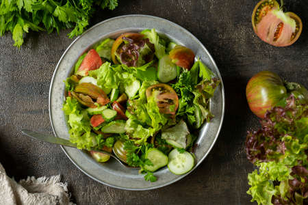Fresh green salad in metal bowl on wooden table. Rustic style.の写真素材