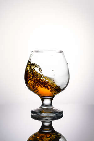 Splash of cognac in glass isolated on a light backgroundの写真素材