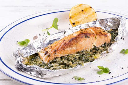 Delicious grilled salmon fish steak on a white plate on white wooden tableの写真素材