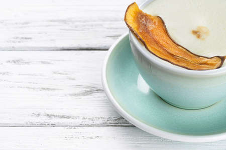 Cup of cappuccino coffee in a blue mug on white wooden backgroundの写真素材