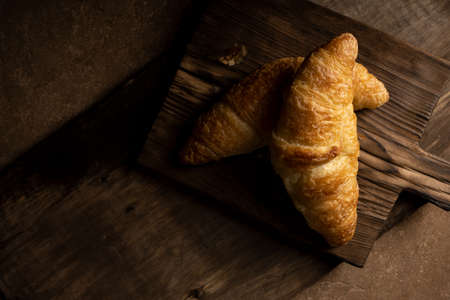 Board with tasty croissants on dark wooden table, closeup. French pastry.の写真素材