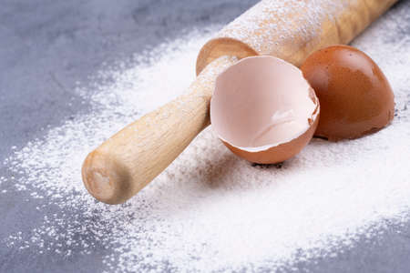 flour and wooden rolling pin on a gray concrete stone table.