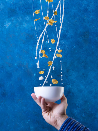 Corn Flakes With Milk Splash. Healthy Breakfast. Levitation on blue background.