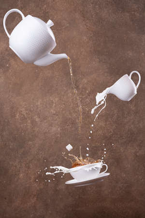 flying cups in pouring hot tea from teapot on a brown background. Levitationの写真素材