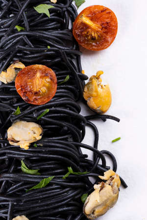 Squid ink pasta with seafood: mussels on a white plate on a white wooden backgroundの写真素材