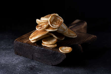 Stack of pancakes with berries on wooden board. Dark wooden background.の写真素材