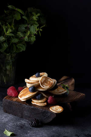 Stack of pancakes with berries on wooden board. Dark wooden background.の写真素材