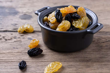 golden and black raisins on wooden table background