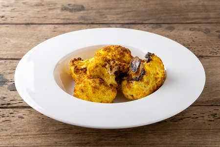 baked cauliflower with curry on white plateの写真素材