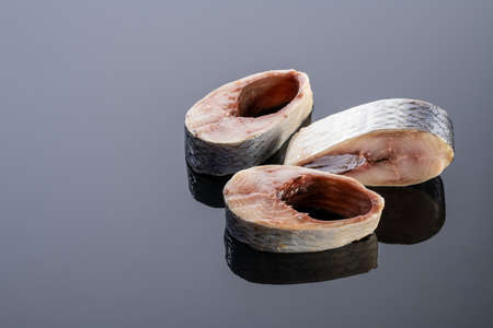pieces of salted herring fish on a mirror background