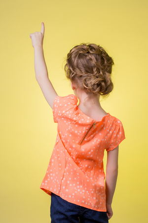 teen girl pointing at copy space on yellow backgroundの写真素材