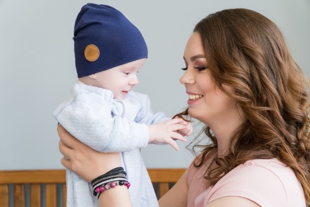 Close-up portrait of happy young mother hugging and kissing his sweet adorable child. Indoors shot, concept imageの写真素材