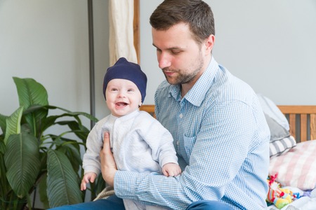 Close-up portrait of happy young father hugging and kissing his sweet adorable child. Indoors shot,...