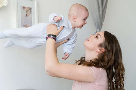 Close-up portrait of happy young mother hugging and kissing his sweet adorable child. Indoors shot,...