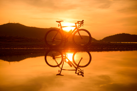 Silhouette road bicycle parked near a lake with reflectionの写真素材