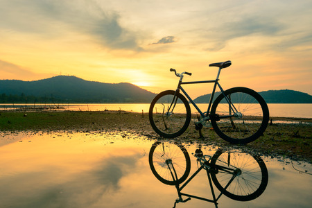 Bicycle parked near a lake with reflectionの写真素材