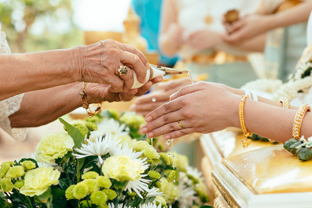 Elder pours ceremonial water into the bride's hand in a Thai traditional wedding ceremonyの写真素材