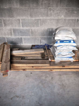 The bags of cement on stack of wood timber and concrete floor in the construction siteの写真素材