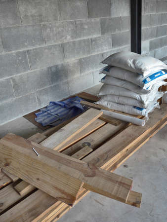 The bags of cement on stack of wood timber and concrete floor in the construction siteの写真素材