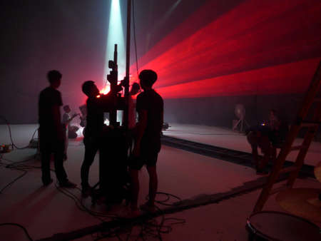 Blurry image and out of focus : Behind the scenes of video shooting production crew team silhouette and camera equipment in studio, Red laser light beamの写真素材