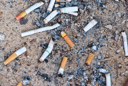Lots of cigarette buds on sandy backgroundの写真素材