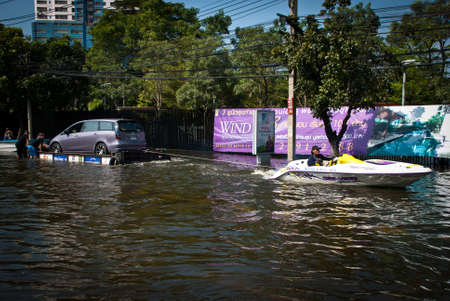 BANGKOK - NOVEMBER 7 2011: Man made car raft is being pulled by jet ski after impact with heaviest flood and rain in 20 years in the capital on November 07, 2011 in Bangkok, Thailand.のeditorial素材