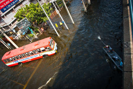 BANGKOK - NOVEMBER 7 2011: A boat and a bus on flooded intersection after impact with heaviest flood and rain in 20 years in the capital on November 07, 2011 in Bangkok, Thailand.のeditorial素材