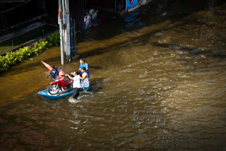 BANGKOK - NOVEMBER 7 2011: Unidentified people travel by boat after impact with heaviest flood and rain in 20 years in the capital on November 07, 2011 in Bangkok, Thailand.のeditorial素材