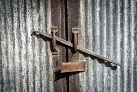 Old metal lock and metal door with wooden pole in the middle.の写真素材