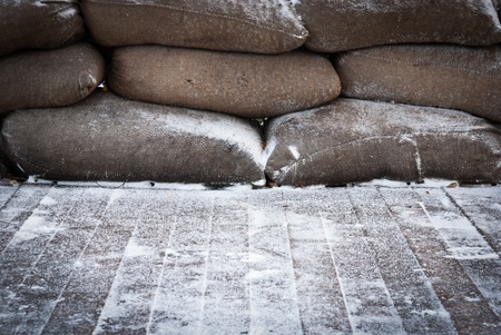 Old brown sandbags on snow covered wooden floor, taken on a winter morning.の写真素材
