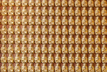 Hundreds of golden Buddha statues background at chinese templeの写真素材