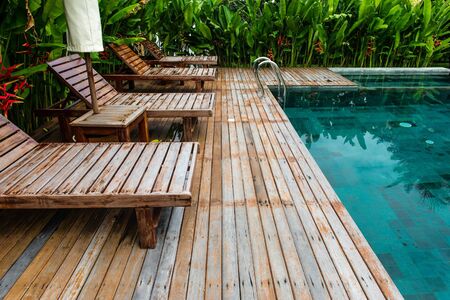 Small swimming pool with wooden setting surrounded by trees, taken on a sunny dayの写真素材