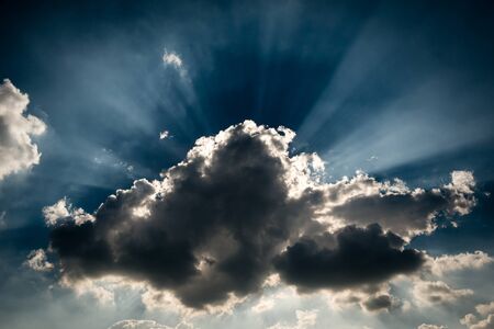 A storm grey cloud blocking the sun, giving the ray of light at the background