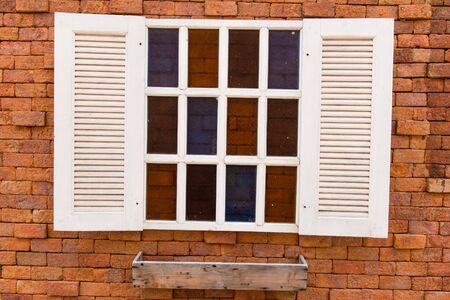 White window frame on a red brick wall with flowers, taken on a sunny day