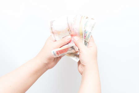 Asian woman holding multiple bank notes, isolatedの写真素材