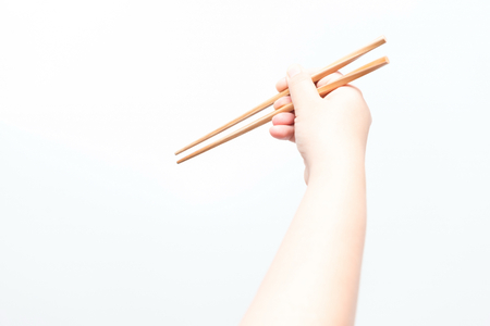 Asian woman holding brown chop stick, isolatedの写真素材