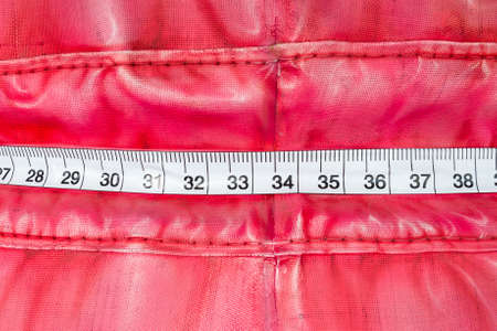 Measure tape wrap around a plastic red bag at close upの写真素材