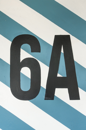 Number six on the concrete wall in car park space with blue and white line for abstract concept...