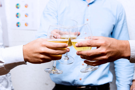 Young business team celebrating successful assignment completion. Office party three men cheering beer in cocktail glass.の写真素材
