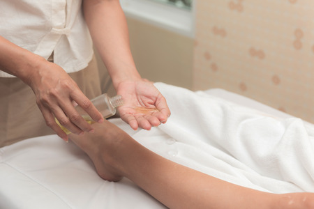 Asian exotic holiday spa concept. Beautiful young white woman enjoy relaxing during foot massage at spa, taken indoor in real spa location.の写真素材