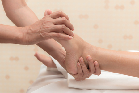 Asian exotic holiday spa concept. Beautiful young white woman enjoy relaxing during foot massage at spa, taken indoor in real spa location.の写真素材