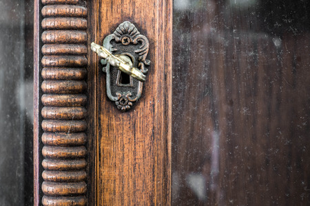 Vintage keyhole with key on vintage wooden cabinet with white backgroundの写真素材