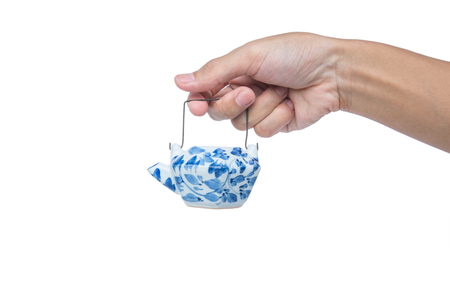 Hand holding mini classic teapot, isolated on white backgroundの写真素材